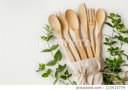 Bamboo cooking utensils wrapped in a cloth with fresh green leaves on a white background 115615774