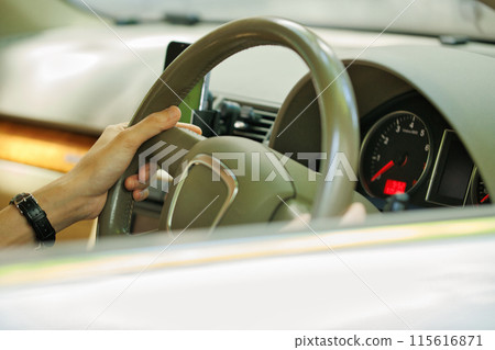 一個穿著西裝的年輕人握著方向盤 115616871