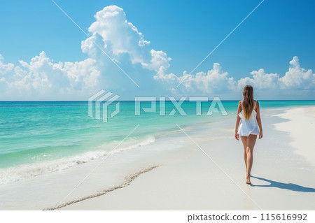 Tranquil woman walking on the serene beach sand, enjoying the relaxation and solitude of a summer beach vacation, with the beautiful blue ocean and sky in the background 115616992