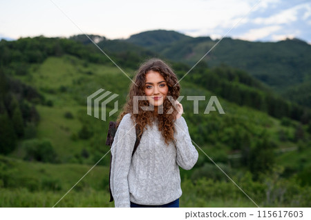 Young tourist woman traveller with backpack walking in nature. Active hiker on trail in mountains enjoying sunset. Young tourist woman traveller with backpack walking in nature. Active hiker on trail in mountains enjoying sunset. 115617603