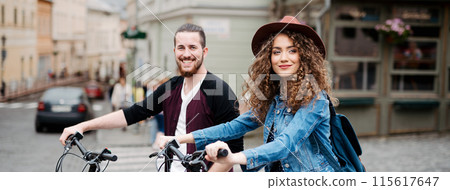 Travellers couple on electric scooters in small city, sightseeing. Young tourist using bikes during their summer trip, vacation. Banner with copy space. 115617647