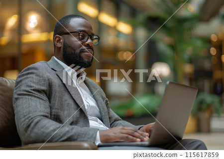 African American businessman sitting in the hotel lobby working with laptop. Business travel concept 115617859