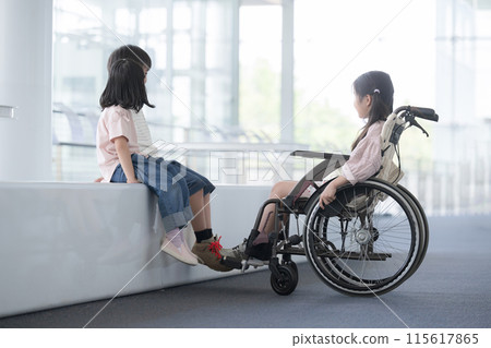 An elementary school student in a wheelchair and a friend talking at eye level - an image of a barrier-free mind An elementary school student in a wheelchair and a friend talking at eye level - an image of a barrier-free mind 115617865