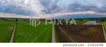 Aerial view captures green farmlands under cloudy sky, showcasing nature and agriculture Aerial view captures green farmlands under cloudy sky, showcasing nature and agriculture 115618396