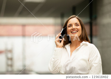 Business Communication Offer. Happy Young Businesswoman Talking On Mobile Phone, Communicating And Smiling Having Successful Conversation With Client Standing Indoors, Empty Space For Text Business Communication Offer. Happy Young Businesswoman Talking On Mobile Phone, Communicating And Smiling Having Successful Conversation With Client Standing Indoors, Empty Space For Text 115618402