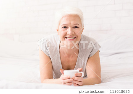 Senior woman enjoying hot fresh coffee, lying in bed, panorama with free space Senior woman enjoying hot fresh coffee, lying in bed, panorama with free space 115618625