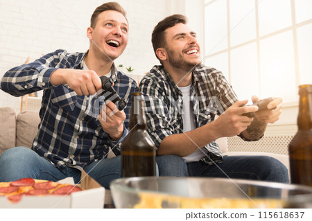 Excited men playing video game, having home party and drinking beer Excited men playing video game, having home party and drinking beer 115618637
