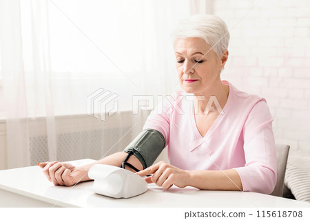 Senior woman measuring her blood pressure at home, free space 115618708