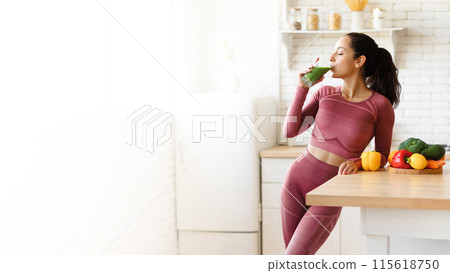 Healthy Nutrition. Young Sporty Lady In Fitwear Drinking Glass Of Green Smoothie In Kitchen, Panorama With Copy Space For Text. Woman Enjoying Healthy Detox Drink Slimming On A Weight Loss Diet Healthy Nutrition. Young Sporty Lady In Fitwear Drinking Glass Of Green Smoothie In Kitchen, Panorama With Copy Space For Text. Woman Enjoying Healthy Detox Drink Slimming On A Weight Loss Diet 115618750