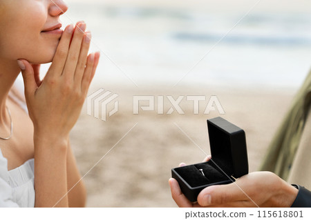 Engagement. Man asking his girlfriend the marriage question, proposing marry him on the beach, closeup, cropped. Love, relationship concept Engagement. Man asking his girlfriend the marriage question, proposing marry him on the beach, closeup, cropped. Love, relationship concept 115618801