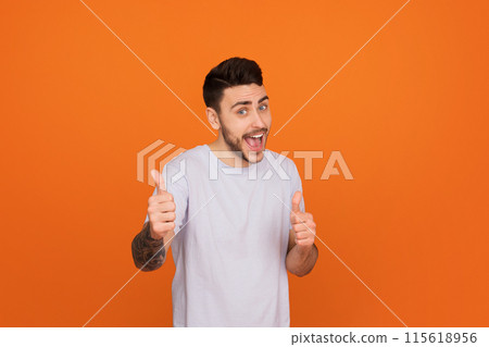 A cheerful european guy gives a thumbs up, symbolizing approval and positivity, showcasing friendship A cheerful european guy gives a thumbs up, symbolizing approval and positivity, showcasing friendship 115618956