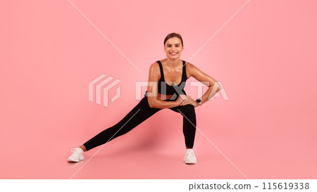 Fitness Routine. Smiling Sporty Woman Doing Side Lunge Exercise, Happy Motivated Young Female Stretching Legs, Athletic Millennial Lady Training Over Pink Studio Background, Copy Space 115619338