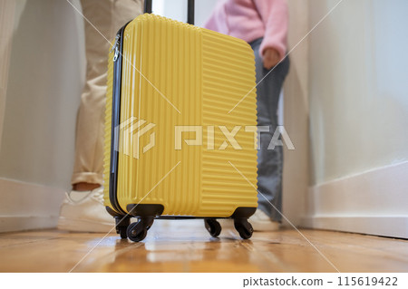 Vacation Accomodation. Closeup Of Yellow Travel Suitcase While Unrecognizable Tourists Couple Entering Their Hotel Room, Posing In Doorway Indoor. Tourism Concept. Cropped Shot 115619422