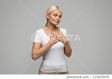 Heart Attack. Mature blonde woman suffering from severe chest pain, senior female feeling unwell, facing signs of myocardial infarction disease, standing on grey studio background, copy space Heart Attack. Mature blonde woman suffering from severe chest pain, senior female feeling unwell, facing signs of myocardial infarction disease, standing on grey studio background, copy space 115620076