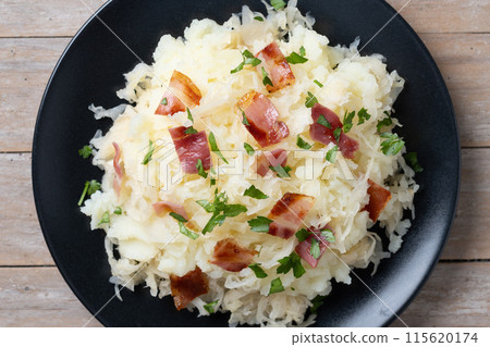 Slovak potato dumplings halusky with steamed sauerkraut and bacon on wooden table 115620174