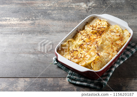 Potato gratin baked with cream and cheese on wooden table 115620187