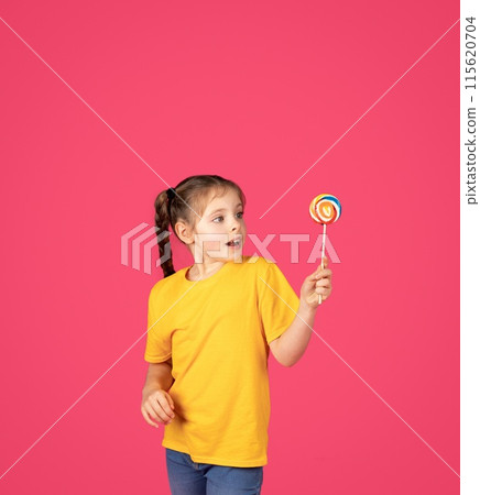 Sweet Treat. Excited Cute Little Girl Holding Colorful Candy In Hand, Amazed Preteen Female Child Looking At Bright Lollipop, Standing Isolated Over Pink Studio Background, Copy Space Sweet Treat. Excited Cute Little Girl Holding Colorful Candy In Hand, Amazed Preteen Female Child Looking At Bright Lollipop, Standing Isolated Over Pink Studio Background, Copy Space 115620704