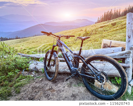 Black electric mountain bike on the dirt trail in the mountains at sunset (no people). Black electric mountain bike on the dirt trail in the mountains at sunset (no people). 115620743