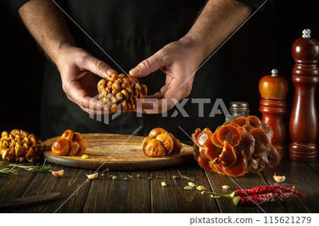 The cook hands sort fresh wild enoki mushrooms before cooking. The concept of cooking wild mushrooms Velvet shank in a restaurant kitchen. The cook hands sort fresh wild enoki mushrooms before cooking. The concept of cooking wild mushrooms Velvet shank in a restaurant kitchen. 115621279