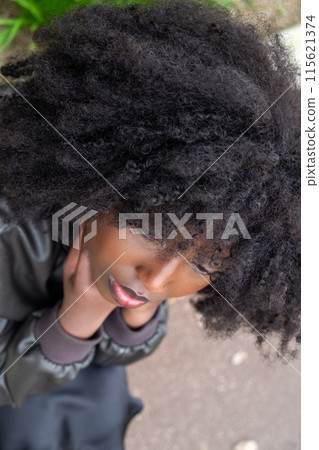 Stylish woman with curly hair in city, showing fashion and beauty trends with elegance 115621374