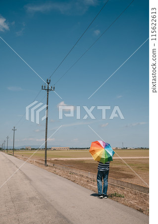 man with a rainbow umbrella on his shoulders 115622613