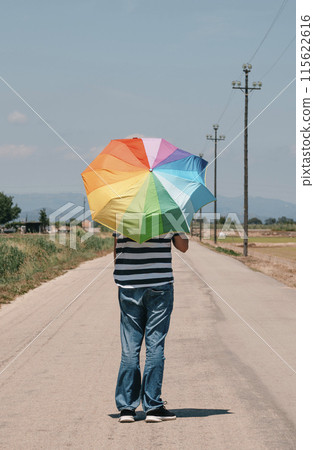 man carrying a rainbow umbrella on his shoulders man carrying a rainbow umbrella on his shoulders 115622616