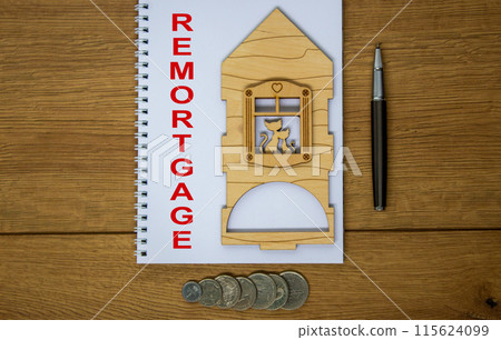White note with inscription 'remortgage' on beautiful wooden table, metalic pen, coins and miniature wooden house. Business concept. 115624099