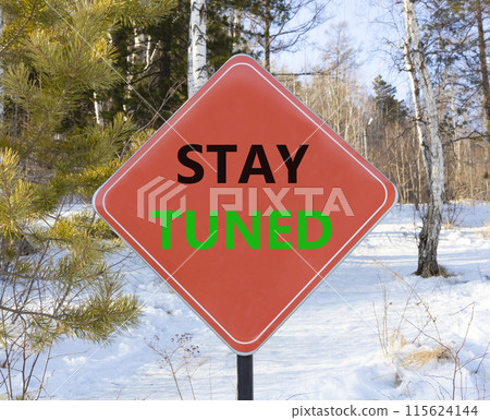 Stay tuned symbol. Concept words Stay tuned on beautiful red road sign. Beautiful forest snow blue sky background. Business, support, motivation, psychological and stay tuned concept. Copy space. 115624144