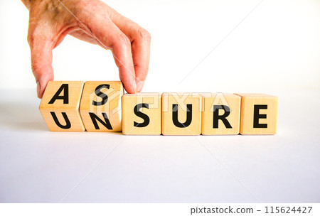 Assure or unsure symbol. Businessman turns wooden cubes and changes the concept word unsure to assure. Beautiful white table, white background, copy space. Business and assure or unsure concept. 115624427