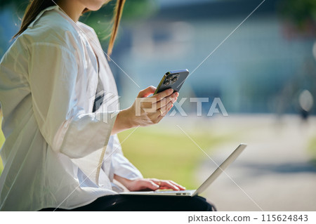 在公園裡經營智能手機的年輕女子 115624843