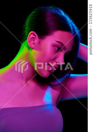Wellness and attraction., Elegant young girl with well-kept skin and hair posing against black studio background in neon light 115625918