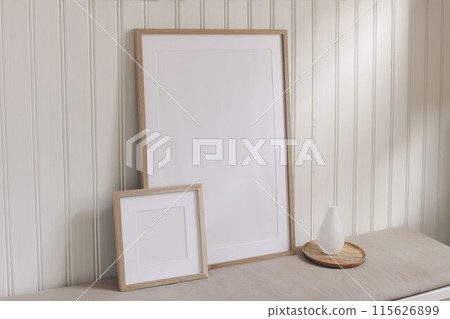 Set of blank portrait and square wooden picture frame mockups. Bench with modern glass vase on tray. White wooden beadboard wall panelling background. Elegant home interior decor still life 115626899