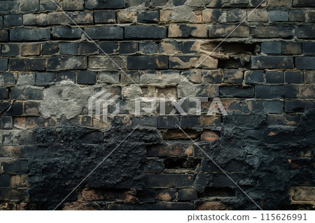Close-up of an old brick wall with a distinctive black texture and signs of decay 115626991