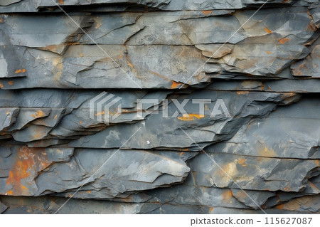 Close up of weathered slate rock texture with a natural grey and orange earthy pattern, perfect for background, architecture, or building materials Close up of weathered slate rock texture with a natural grey and orange earthy pattern, perfect for background, architecture, or building materials 115627087