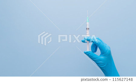 Doctor's hand in blue medical glove holding a syringe on blue background. Concept of vaccination, world Immunization, medical treatment, cosmetic procedures. Health care and medical. Doctor's hand in blue medical glove holding a syringe on blue background. Concept of vaccination, world Immunization, medical treatment, cosmetic procedures. Health care and medical. 115627148