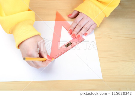 Drawing lines with a pencil and triangular ruler. Drawing lines with a pencil and triangular ruler. 115628342