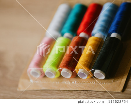Multicolored sewing threads on paper bobbins and spools in blister packs. Threads for needlework, hobbies and recreation. Necessary item for every family. Materials for clothing repair and embroidery Multicolored sewing threads on paper bobbins and spools in blister packs. Threads for needlework, hobbies and recreation. Necessary item for every family. Materials for clothing repair and embroidery 115628764