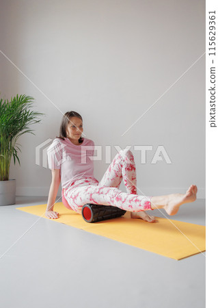 person works out in gym or home with foam roller. exercises for back, legs, hips, arms 115629361