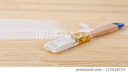 white paint with a brush on a wooden background with texture 115629724