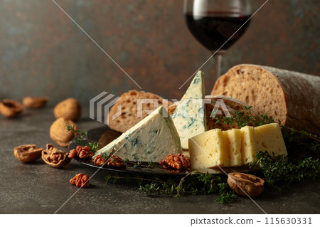 Cheese, bread, red wine, and walnuts on a stone table. Cheese, bread, red wine, and walnuts on a stone table. 115630331