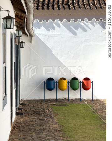 Colorful Waste Bins Lined Against a Whitewashed Wall Colorful Waste Bins Lined Against a Whitewashed Wall 115631082