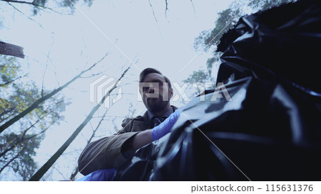 Male detective peers into a body bag, his expression one of shock at the gruesome sight Male detective peers into a body bag, his expression one of shock at the gruesome sight 115631376