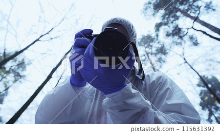 Male forensic scientist photographs a murder victim beneath a body bag at the crime scene 115631392