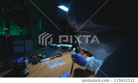 Man in a protective suit makes an improvised explosive device in his own laboratory Man in a protective suit makes an improvised explosive device in his own laboratory 115631512