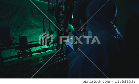 Laboratory scientist at a plant reads a plan while examining tubes, involved in criminal activity Laboratory scientist at a plant reads a plan while examining tubes, involved in criminal activity 115631532