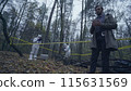 Forensic experts working with evidence in a forest, detective taking notes about the crime scene 115631569