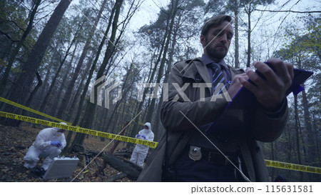 Police officer writing a report on a crime scene examination, evidence collection 115631581