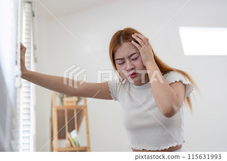 Young Woman Suffering from a Severe Headache at Home, Holding Her Head in Pain 115631993