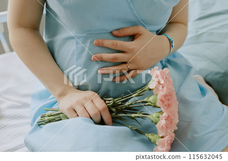 Pregnant woman touching her belly with love and holding beautiful bouquet of flowers Pregnant woman touching her belly with love and holding beautiful bouquet of flowers 115632045