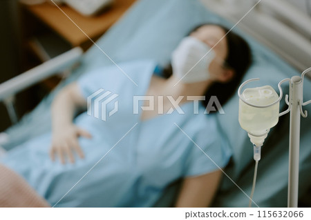 Medium close up of irrigation tubing set and pregnant woman lying on bed in background 115632066